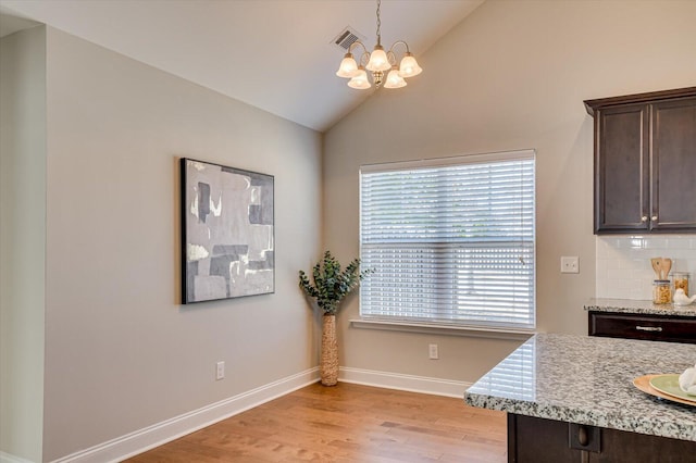 dining area featuring light wood-type flooring, visible vents, a notable chandelier, baseboards, and lofted ceiling