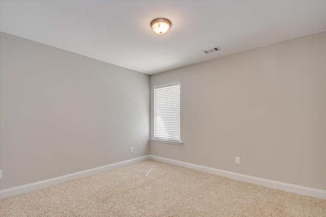 unfurnished room with visible vents, light colored carpet, and baseboards