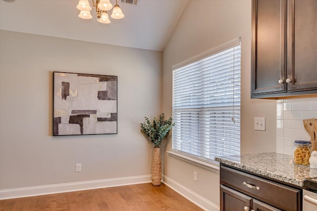 dining space with baseboards, visible vents, an inviting chandelier, vaulted ceiling, and light wood-style floors