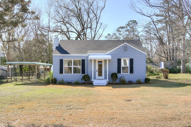 view of front of house featuring a chimney, a front lawn, and a detached carport