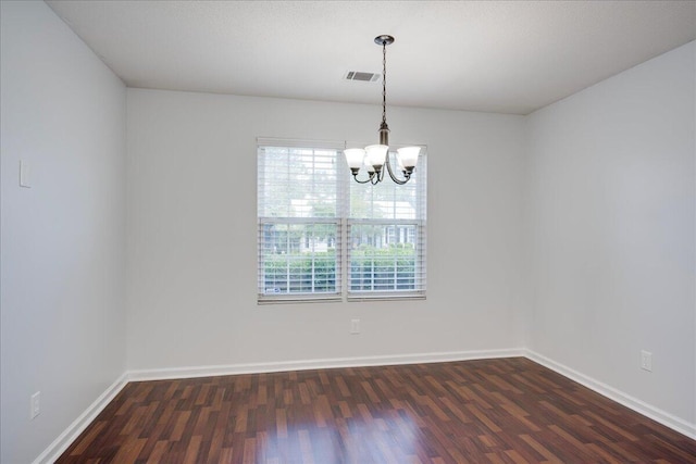 spare room with dark wood-type flooring, a chandelier, and baseboards