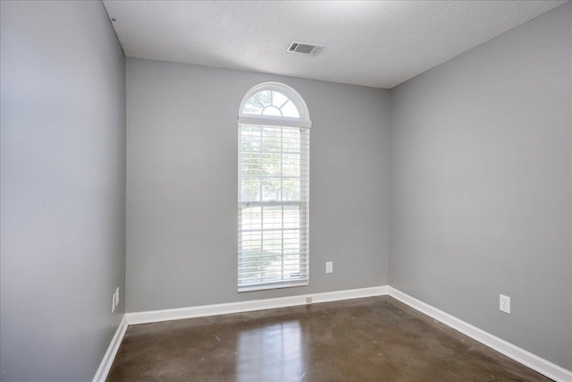 spare room with concrete floors, baseboards, and a textured ceiling
