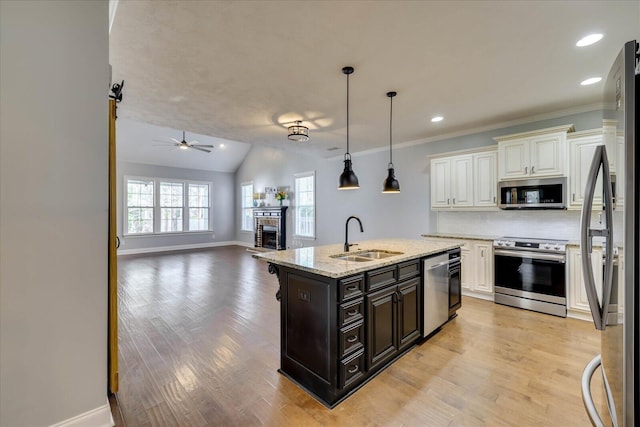 951 Napiers Post Dr, Evans, GA 30809 - kitchen with appliances with stainless steel finishes, a brick fireplace, tasteful backsplash, light wood-type flooring, and a kitchen island with sink