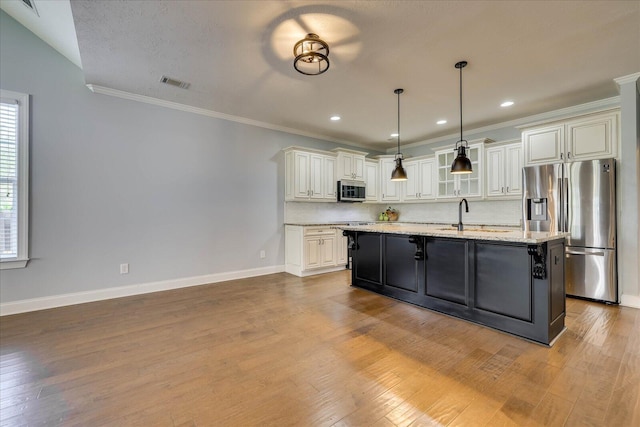951 Napiers Post Dr, Evans, GA 30809 - kitchen featuring appliances with stainless steel finishes, ornamental molding, a center island with sink, light stone counters, and wood finished floors