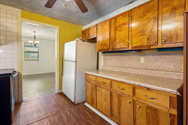 kitchen with dark hardwood / wood-style floors, ceiling fan with notable chandelier, decorative backsplash, white refrigerator, and a textured ceiling