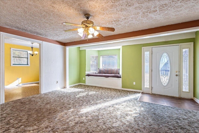 carpeted entryway with ceiling fan with notable chandelier, a textured ceiling, and a wealth of natural light