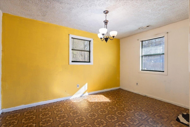 unfurnished room featuring an inviting chandelier and a textured ceiling