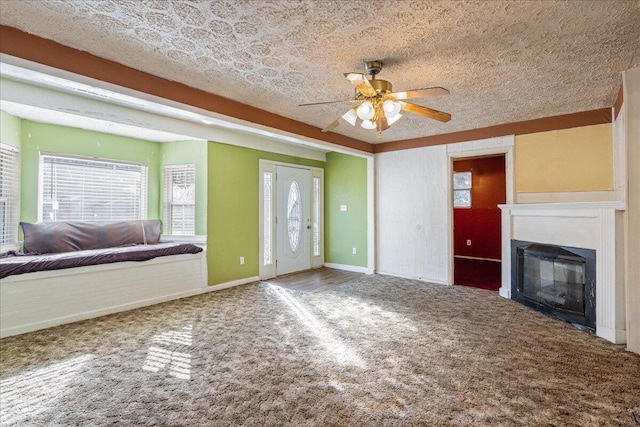 unfurnished living room featuring ceiling fan, carpet, and a textured ceiling