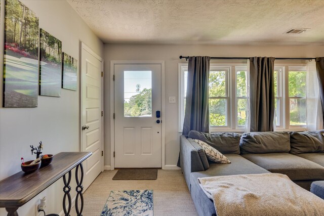 doorway with baseboards, light carpet, a textured ceiling, and visible vents