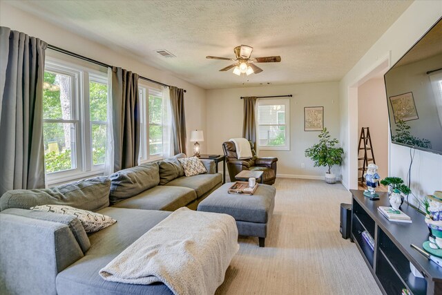 living room with a textured ceiling, visible vents, light carpet, and ceiling fan