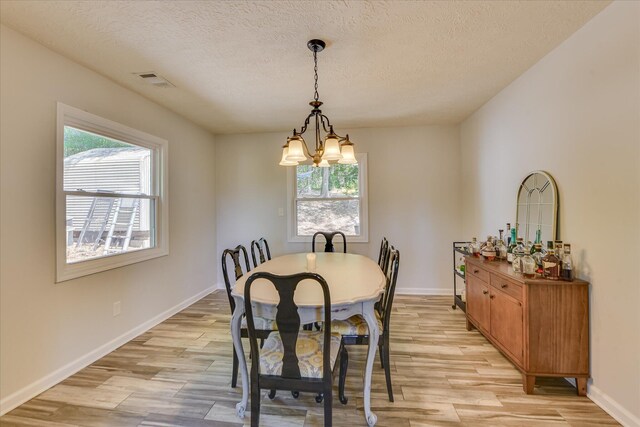 dining space featuring light wood-style floors, a healthy amount of sunlight, and an inviting chandelier