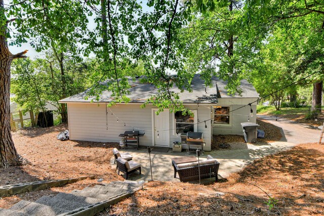back of property with a patio and a shingled roof