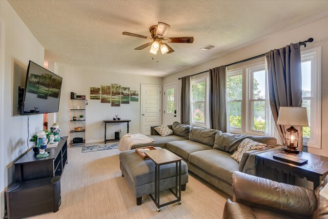 living room with ceiling fan, light colored carpet, a textured ceiling, and visible vents