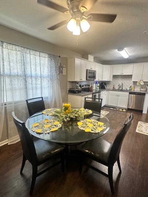 dining space with baseboards, a ceiling fan, and dark wood-style flooring