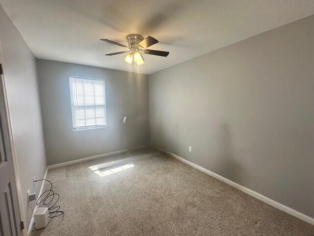 carpeted empty room with baseboards and ceiling fan