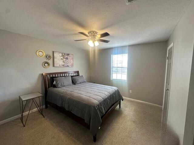 bedroom with baseboards, carpet floors, a textured ceiling, and a ceiling fan