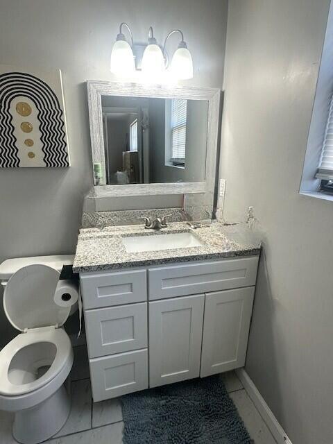 bathroom with marble finish floor, baseboards, toilet, and vanity