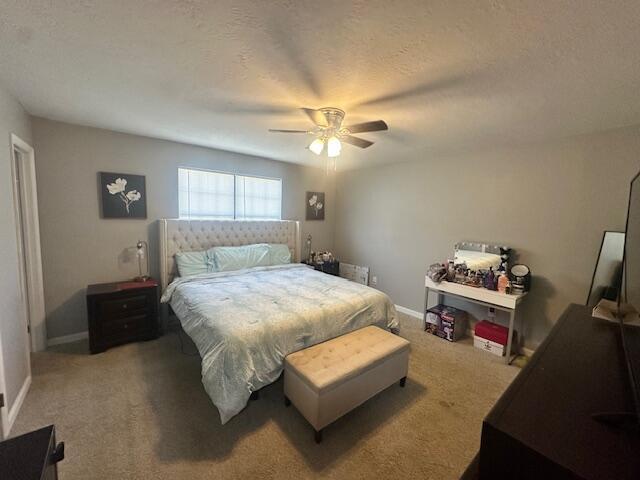 bedroom with light carpet, baseboards, a ceiling fan, and a textured ceiling