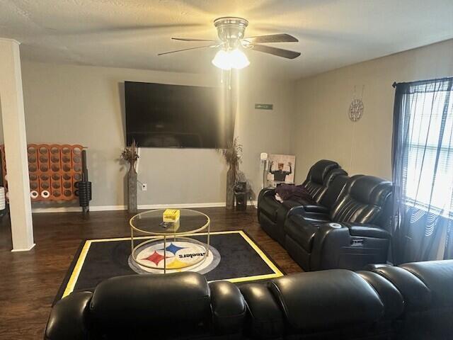 living room featuring a ceiling fan, baseboards, and wood finished floors