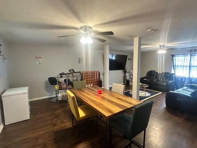 dining space featuring dark wood-style flooring, a textured ceiling, baseboards, and ceiling fan