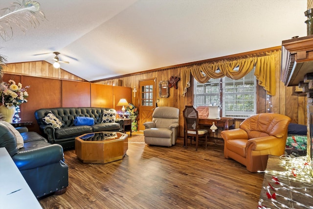 living area featuring lofted ceiling, ceiling fan, a textured ceiling, wood walls, and dark wood-style flooring