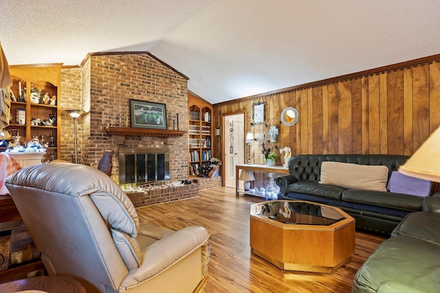 living room featuring a textured ceiling, wooden walls, a fireplace, wood finished floors, and vaulted ceiling