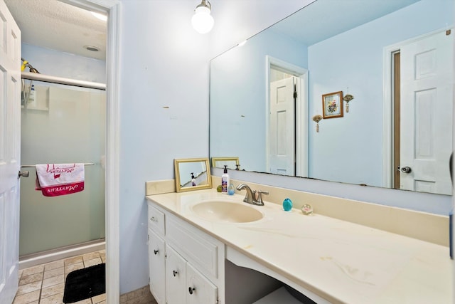 full bath featuring a textured ceiling, tile patterned flooring, a shower stall, and vanity