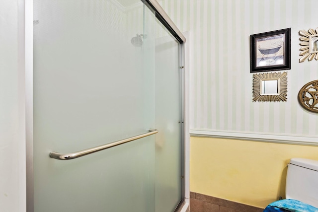 bathroom featuring a shower stall, toilet, and wallpapered walls