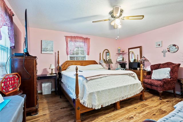 bedroom with multiple windows, a textured ceiling, and wood finished floors