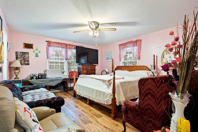 bedroom with ceiling fan, a textured ceiling, and wood finished floors