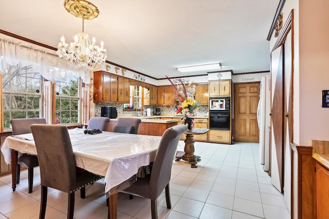 dining space with light tile patterned floors, ornamental molding, and a chandelier