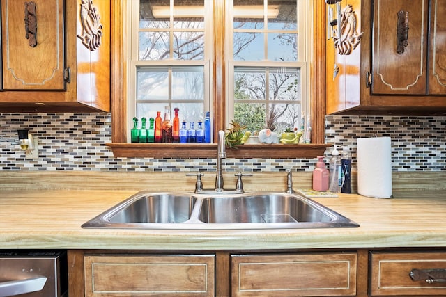 kitchen with brown cabinets, light countertops, a sink, and decorative backsplash