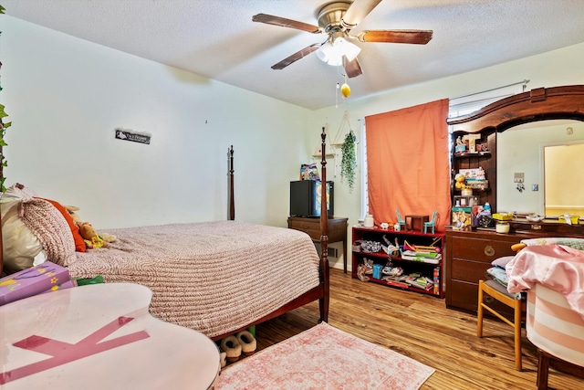 bedroom featuring light wood-type flooring, a ceiling fan, and a textured ceiling