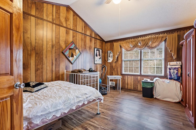 bedroom featuring a ceiling fan, wood finished floors, vaulted ceiling, a textured ceiling, and wood walls