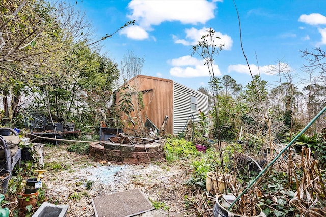 view of yard with a fire pit and an outdoor structure