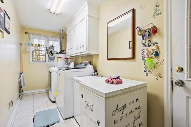 washroom with light tile patterned floors, gas water heater, baseboards, washer and dryer, and cabinet space