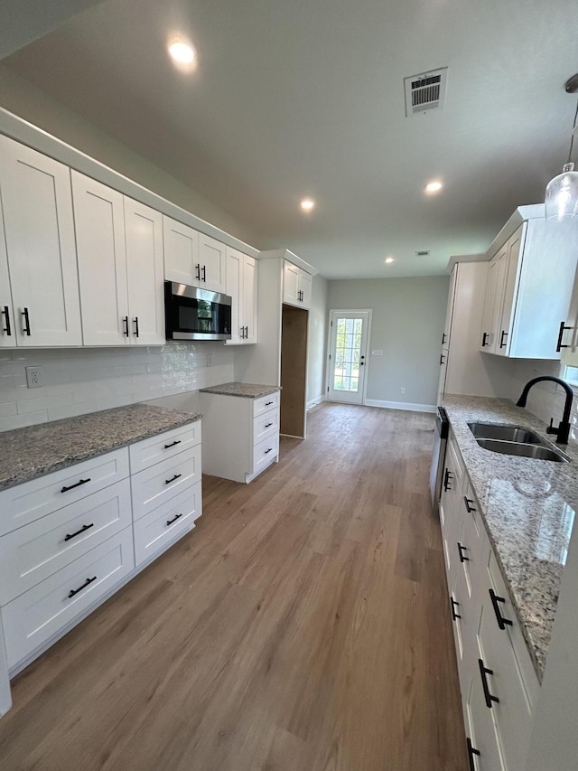 410 Williams St, Grovetown, GA 30813 - kitchen with stainless steel microwave, a sink, light stone counters, white cabinetry, and backsplash
