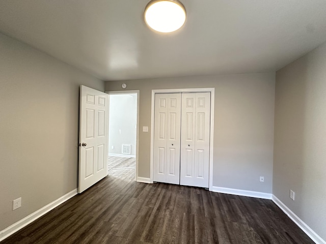 unfurnished bedroom featuring a closet and dark wood-type flooring