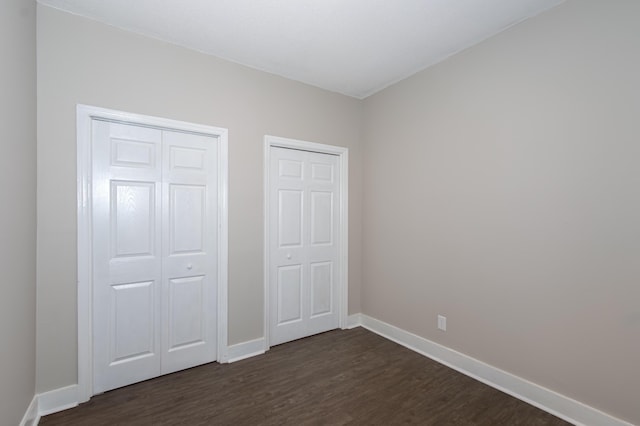 unfurnished bedroom featuring two closets and dark hardwood / wood-style floors