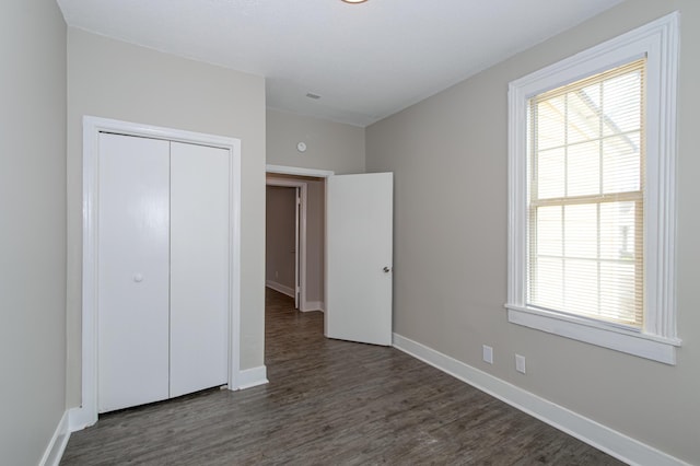 unfurnished bedroom with dark hardwood / wood-style flooring and a closet