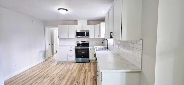 1306 Dominica Dr, Augusta, GA 30909 - kitchen with stainless steel appliances, a sink, light wood-style flooring, baseboards, and decorative backsplash