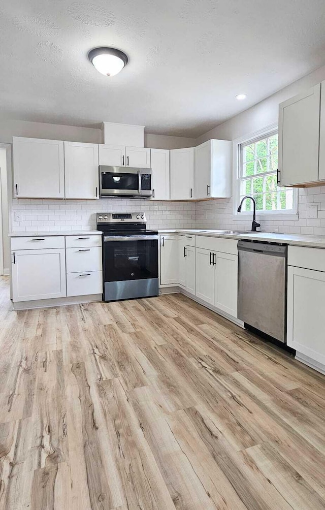 1306 Dominica Dr, Augusta, GA 30909 - kitchen with appliances with stainless steel finishes, light wood-style flooring, tasteful backsplash, light countertops, and white cabinets