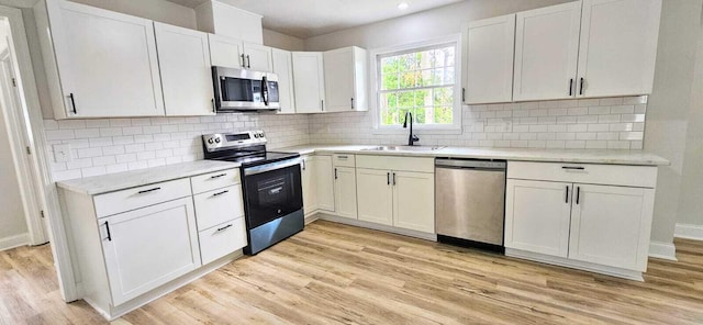 1306 Dominica Dr, Augusta, GA 30909 - kitchen featuring stainless steel appliances, a sink, light wood-type flooring, white cabinets, and decorative backsplash