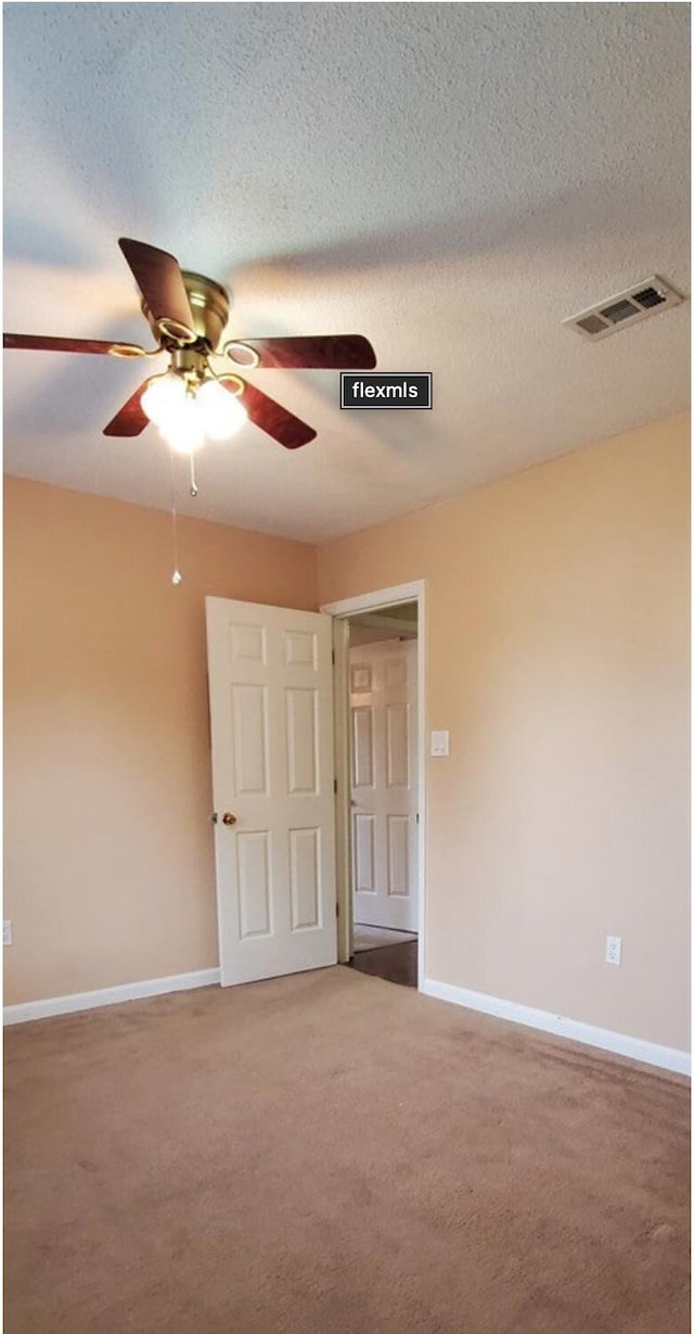 spare room with carpet flooring, ceiling fan, and a textured ceiling