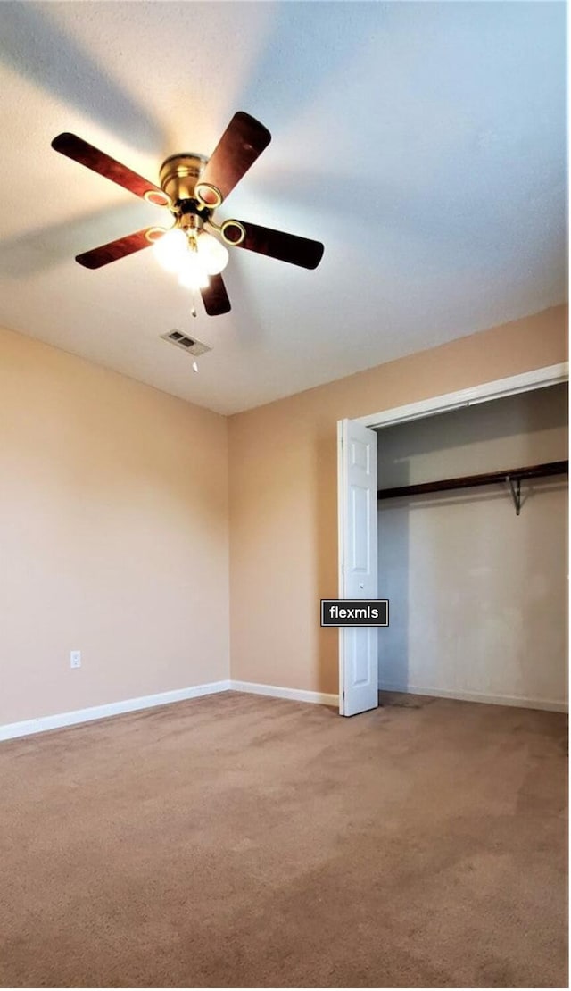 unfurnished bedroom featuring carpet, ceiling fan, and a closet