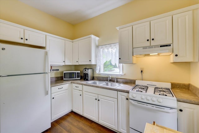 kitchen with white cabinetry, under cabinet range hood, a sink, and white appliances