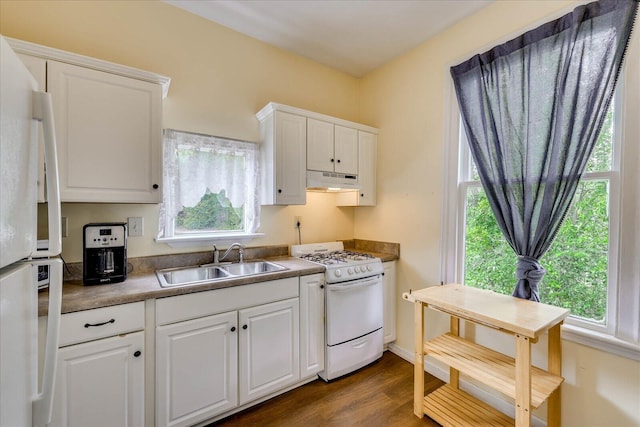 kitchen featuring under cabinet range hood, a sink, white appliances, and a wealth of natural light