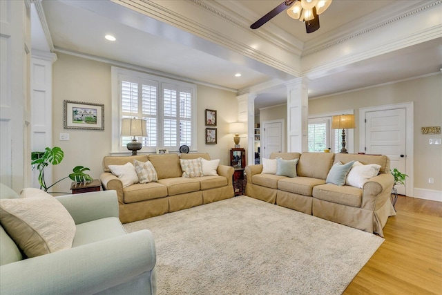 living area featuring crown molding, ceiling fan, ornate columns, and light wood finished floors