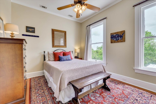 bedroom with crown molding, visible vents, baseboards, and wood finished floors