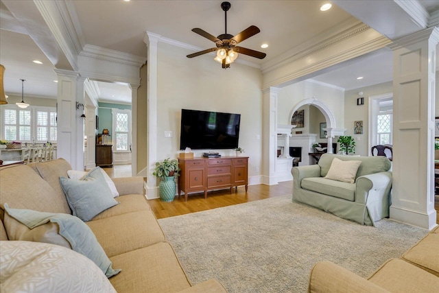 living area with plenty of natural light, ornate columns, a ceiling fan, and crown molding